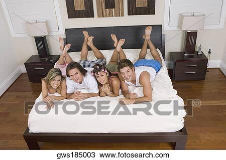 High angle view of four friends lying on the bed View Large Photo Image Stock Image - High angle view of four friends lying on the bed. Fotosearch