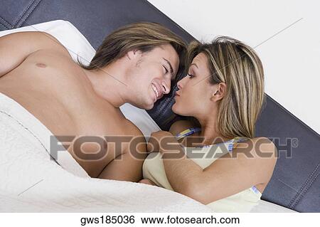 Young couple lying together on the bed View Large Photo Image Stock Photograph - Young couple lying together on the bed. Fotosearch