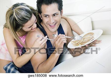 Young man holding a plate of pancakes with a young woman lying on him and smiling View Large Photo Image Stock Photo - Young man holding a plate of pancakes with a young woman lying on him and smiling. Fotosearch