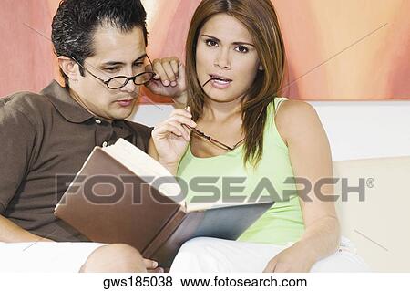 Young man sitting with a young woman reading a book View Large Photo Image Stock Photo - Young man sitting with a young woman reading a book. Fotosearch