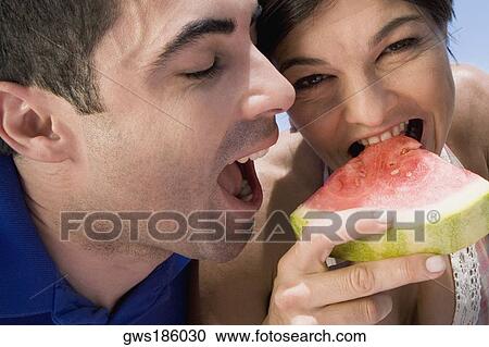Close-up of a mid adult couple eating a slice of watermelon View Large Photo Image Stock Image - Close-up of a mid adult couple eating a slice of watermelon. Fotosearch
