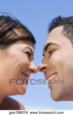 Stock Photograph - Close-up of a mid adult couple looking at each other with smiling. Fotosearch