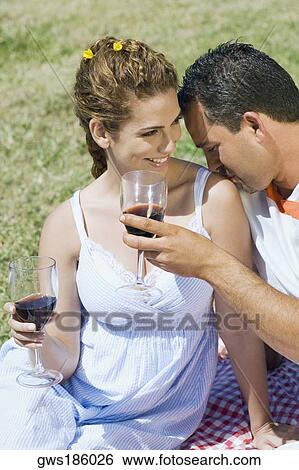 Stock Photograph - Mid adult man holding a wine glass and kissing on a mid adult woman's shoulder. Fotosearch