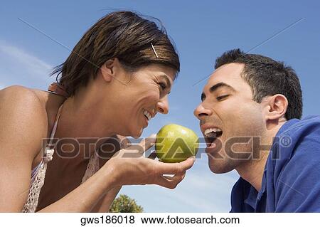 Mid adult woman feeding a green apple to a mid adult man View Large Photo Image Stock Photo - Mid adult woman feeding a green apple to a mid adult man. Fotosearch