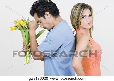 Portrait of a young woman standing with a young man holding flowers View Large Photo Image Stock Image - Portrait of a young woman standing with a young man holding flowers. Fotosearch