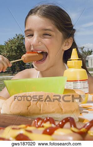 Girl eating a sausage in a picnic View Large Photo Image Stock Image - Girl eating a sausage in a picnic. Fotosearch