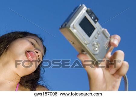 Low angle view of a girl taking a photograph of herself View Large Photo Image Stock Photograph - Low angle view of a girl taking a photograph of herself. Fotosearch