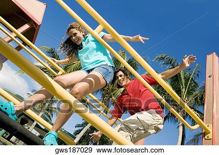 Low angle view of a mid adult couple standing on a jungle gym and smiling View Large Photo Image Stock Photo - Low angle view of a mid adult couple standing on a jungle gym and smiling. Fotosearch