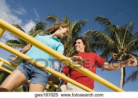 Stock Photography - Low angle view of a mid adult couple standing on a jungle gym and smiling. Fotosearch