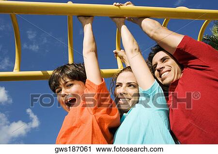 Mid adult couple hanging on monkey bars with their son and smiling View Large Photo Image Stock Image - Mid adult couple hanging on monkey bars with their son and smiling. Fotosearch