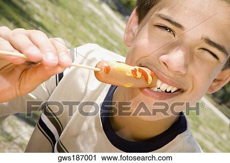Stock Image - Portrait of a boy eating a sausage. Fotosearch
