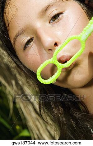 Portrait of a girl holding a bubble wand and blowing bubbles View Large Photo Image Picture - Portrait of a girl holding a bubble wand and blowing bubbles. Fotosearch