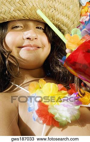 Stock Image - Portrait of a girl with a glass of mocktail and smirking. Fotosearch