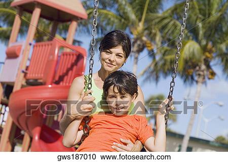Portrait of a mid adult woman swinging on a swing with her son and smiling View Large Photo Image Stock Image - Portrait of a mid adult woman swinging on a swing with her son and smiling. Fotosearch