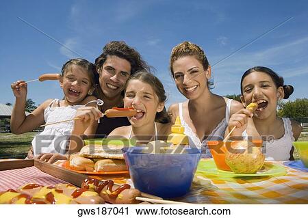 Three girls eating sausages with their parents in a picnic View Large Photo Image Stock Image - Three girls eating sausages with their parents in a picnic. Fotosearch