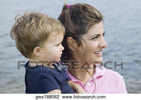 Close-up of a mid adult woman carrying her son and smiling View Large Photo Image Stock Image - Close-up of a mid adult woman carrying her son and smiling. Fotosearch
