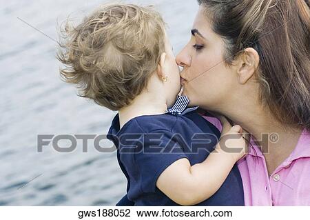 Stock Image - Close-up of a mid adult woman kissing her son. Fotosearch