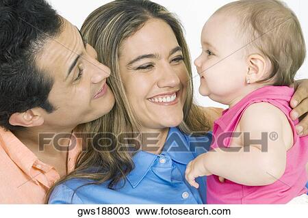 Close-up of a young couple with their daughter smiling View Large Photo Image Stock Image - Close-up of a young couple with their daughter smiling. Fotosearch