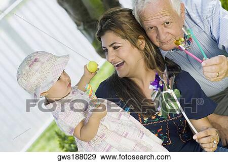 Girl holding a candy with her mother and grandfather View Large Photo Image Stock Photo - Girl holding a candy with her mother and grandfather. Fotosearch