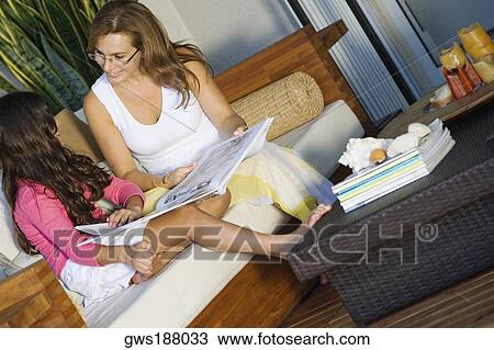 Mature woman and her daughter sitting with a magazine View Large Photo Image Stock Image - Mature woman and her daughter sitting with a magazine. Fotosearch