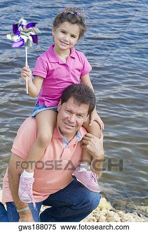 Mid adult man carrying his daughter on his shoulders at the water's edge View Large Photo Image Stock Photography - Mid adult man carrying his daughter on his shoulders at the water's edge. Fotosearch