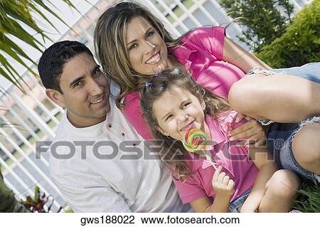Portrait of a girl holding a lollipop with her parents in a park View Large Photo Image Stock Image - Portrait of a girl holding a lollipop with her parents in a park. Fotosearch