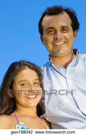 Stock Image - Portrait of a mature man standing with his daughter and smiling. Fotosearch
