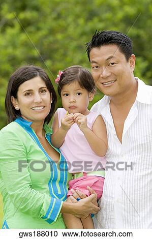Portrait of a mid adult couple posing with their daughter and smiling View Large Photo Image Stock Image - Portrait of a mid adult couple posing with their daughter and smiling. Fotosearch