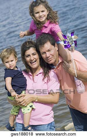Portrait of a mid adult couple with their two children on the coast View Large Photo Image Stock Photo - Portrait of a mid adult couple with their two children on the coast. Fotosearch