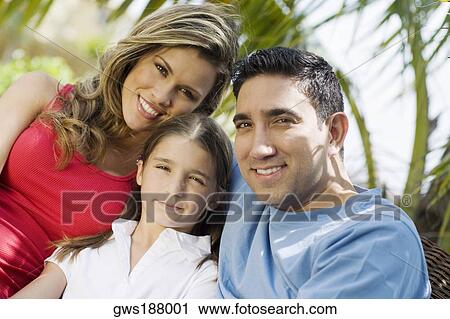 Stock Image - Portrait of a mid adult man and a young woman smiling with a girl. Fotosearch