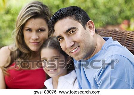 Stock Photograph - Portrait of a mid adult man and a young woman smiling with a girl. Fotosearch