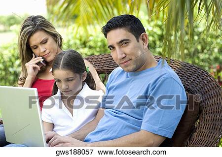 Portrait of a mid adult man using a laptop with a girl and a young woman sitting beside them View Large Photo Image Stock Photo - Portrait of a mid adult man using a laptop with a girl and a young woman sitting beside them. Fotosearch