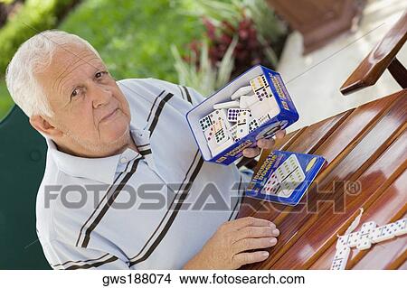 Portrait of a senior man holding a box of dominos View Large Photo Image Picture - Portrait of a senior man holding a box of dominos. Fotosearch