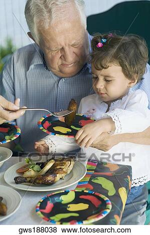 Senior man feeding his granddaughter with a fork View Large Photo Image Stock Photo - Senior man feeding his granddaughter with a fork. Fotosearch