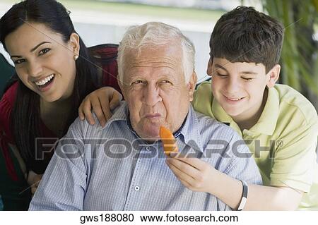 Teenage boy feeding a yellow bell pepper to his grandfather View Large Photo Image Stock Image - Teenage boy feeding a yellow bell pepper to his grandfather. Fotosearch