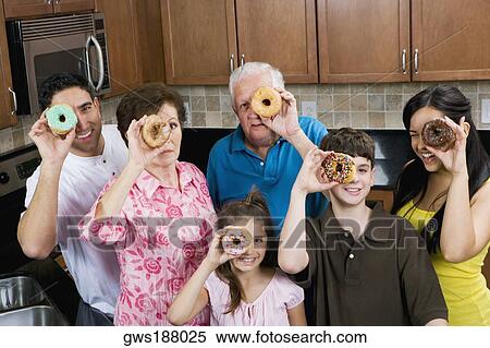 Stock Photography - Three generation family looking through donuts. Fotosearch