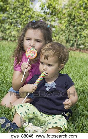 Two sisters sitting in a park and eating candies View Large Photo Image Stock Photograph - Two sisters sitting in a park and eating candies. Fotosearch