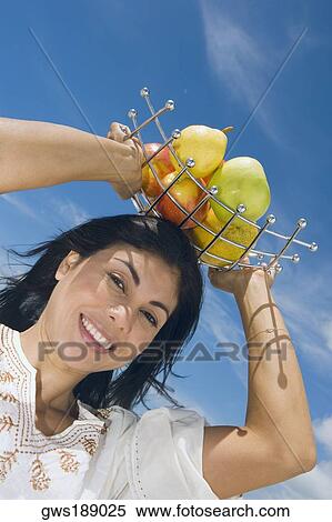 Low angle view of a mid adult woman holding a fruit tray on her head and smiling View Large Photo Image Stock Photography - Low angle view of a mid adult woman holding a fruit tray on her head and smiling. Fotosearch