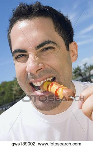 Portrait of a mid adult man eating a sausage View Large Photo Image Stock Image - Portrait of a mid adult man eating a sausage. Fotosearch