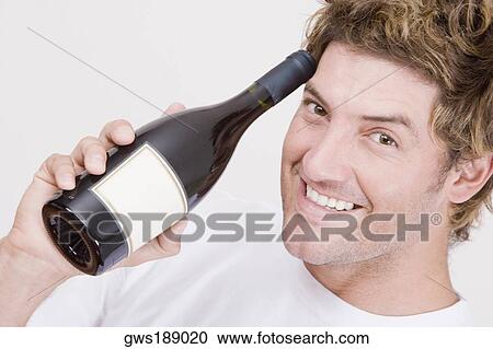 Stock Image - Portrait of a mid adult man holding a champagne bottle and smiling. Fotosearch