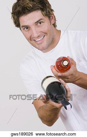 Portrait of a mid adult man holding a wine bottle and a champagne bottle and smiling View Large Photo Image Stock Photograph - Portrait of a mid adult man holding a wine bottle and a champagne bottle and smiling. Fotosearch