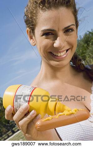 Portrait of a mid adult woman applying mustard on a sausage View Large Photo Image Stock Photo - Portrait of a mid adult woman applying mustard on a sausage. Fotosearch