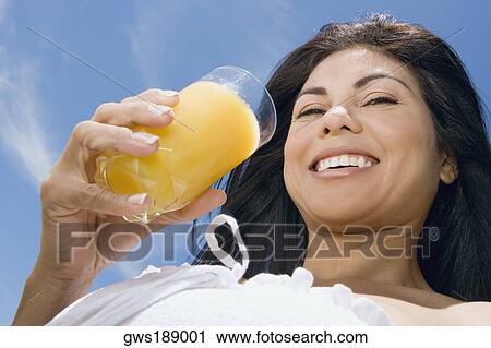Portrait of a mid adult woman holding a glass of orange juice and smiling View Large Photo Image Stock Image - Portrait of a mid adult woman holding a glass of orange juice and smiling. Fotosearch