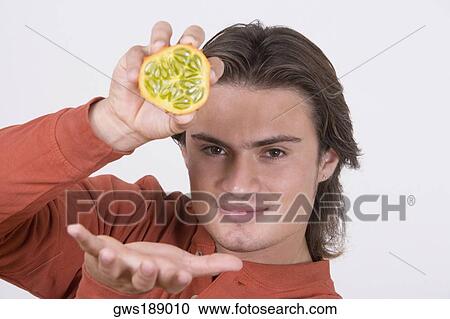 Portrait of a young man holding half of a kawani fruit View Large Photo Image Stock Image - Portrait of a young man holding half of a kawani fruit. Fotosearch