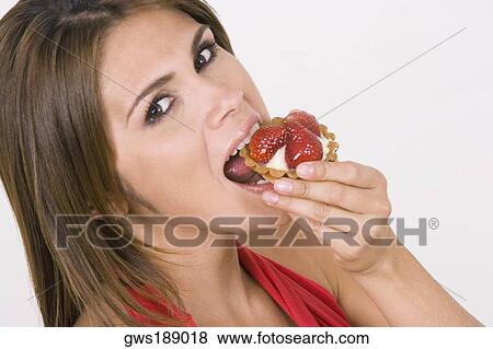 Stock Photo - Portrait of a young woman eating a strawberry tart. Fotosearch