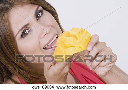 Portrait of a young woman eating cubes of a mango and smiling View Large Photo Image Picture - Portrait of a young woman eating cubes of a mango and smiling. Fotosearch