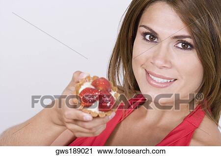 Portrait of a young woman holding a strawberry tart and smiling View Large Photo Image Stock Image - Portrait of a young woman holding a strawberry tart and smiling. Fotosearch