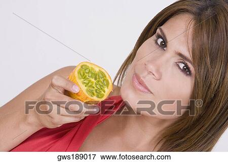 Portrait of a young woman holding a half kawani fruit View Large Photo Image Stock Photo - Portrait of a young woman holding a half kawani fruit. Fotosearch