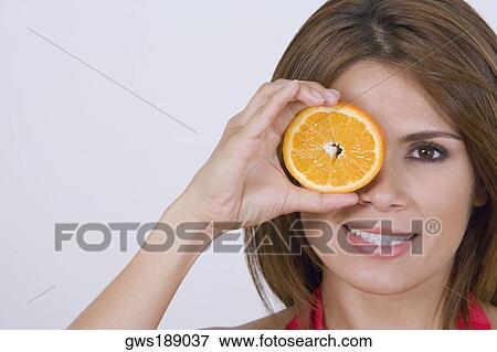 Portrait of a young woman holding a half orange and smiling View Large Photo Image Stock Photo - Portrait of a young woman holding a half orange and smiling. Fotosearch