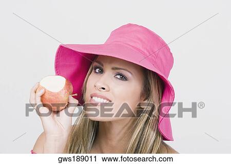 Stock Image - Portrait of a young woman holding an apple and smiling. Fotosearch